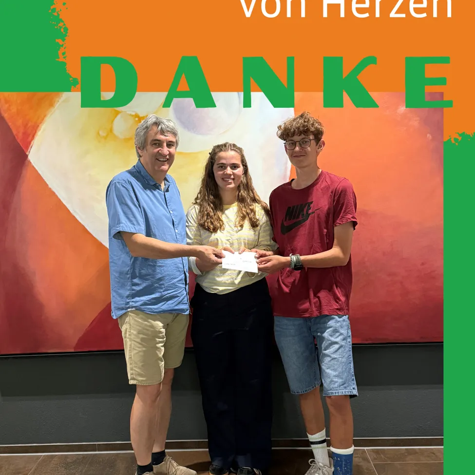 Drei Menschen stehen vor einem großen Gemälde mit den Worten 'Danke' in der Mitte. Der Mann und die Frau lächeln, und der Junge hält ein Stück Papier.