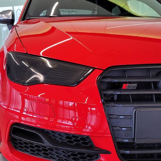 Die Vorderansicht eines roten Audi S3 mit schlanken Scheinwerfern und einem schwarzen Kühlergrill, der einen glänzenden Finish und modernes Design zeigt.