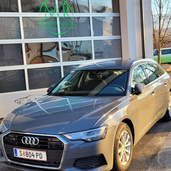 Ein goldfarbener Audi A6 ist vor einem Carwrapping-Unternehmen mit grünem Logo geparkt. Das Auto hat ein Nummernschild mit der Aufschrift S E804 PD.