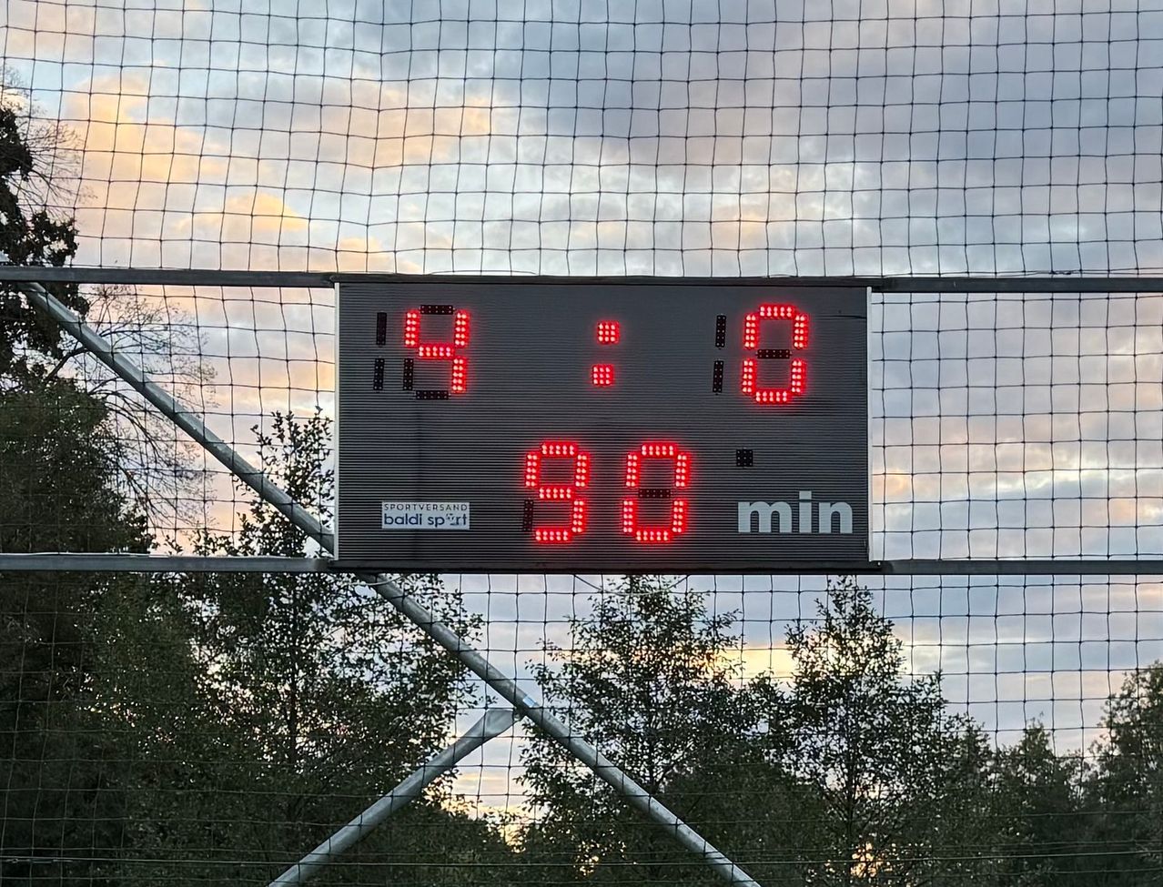 A digital scoreboard displays the score 14 to 18 with 96 minutes remaining. The scoreboard is mounted on a metal fence.