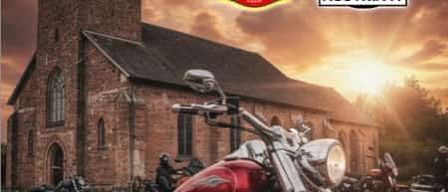 Plakat für ein Motorradtreffen mit einem roten Motorrad vor einer Kirche. Das Datum ist der 17. Mai 2026. Der Text lautet: Fusach Neuer Standort, Segen um 11 Uhr, gefolgt von einer kleinen Fahrt. Arrangements für Essen und Trinken sind getroffen.