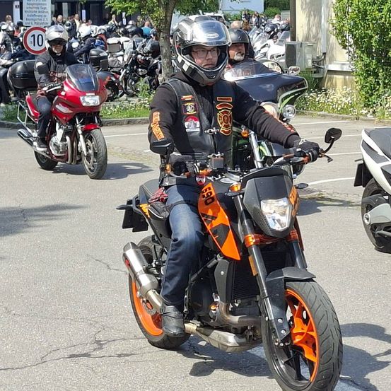 Ein Motorradtreffen mit mehreren Motorradfahrern, die Helme und Jacken tragen und auf der Straße fahren.