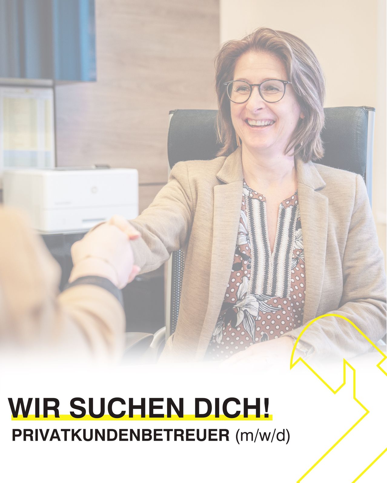 Eine Frau in einem Anzug sitzt in einem Bürostuhl, lächelt und gibt einer anderen Person die Hand. Hinter ihr befinden sich ein Monitor und ein Drucker. Der Text steht in fettem gelbem Schriftzug: 'Wir suchen Dich!'