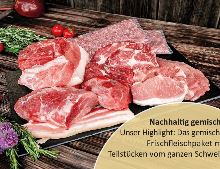 Ein schwarzer Teller mit rohen Fleischstücken und Speckscheiben auf einem Holztisch mit Tomaten und Kräutern. Der Teller hat einen Textüberlagerung mit der Aufschrift 'Nachhaltig und Unser Highlight: Frischfleischpakete'.