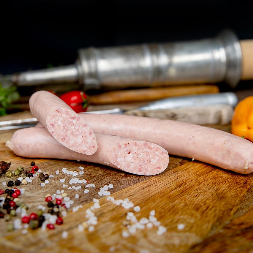 Bratwurst auf Holzbrett mit Pfeffer, Salz und Gemüse