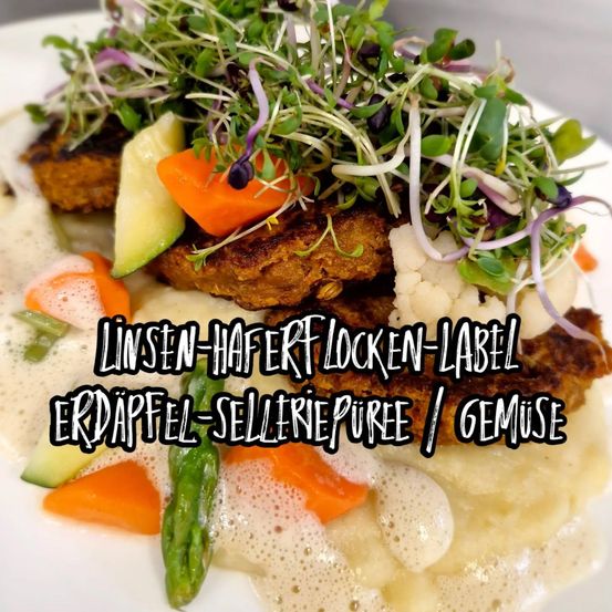 Ein Teller mit Leinsamen-Haferflocken-Patties mit cremiger Sauce, garniert mit Microgreens, Karotten und Spargel. Das Gericht ist mit 'Leinsamen-Haferflocken-Label' und 'Kartoffel-Selleree-Püree/Gemüse' beschriftet.