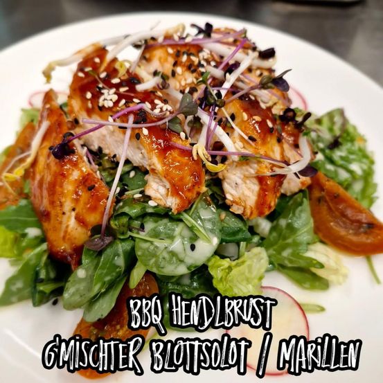 Ein Teller mit gegrilltem Hähnchensalat mit gemischten Salatblättern, Radieschen und Sesam, überzogen mit BBQ-Sauce und garniert mit Microgreens. Das Gericht ist als BBQ Hendbrust Gemischter Blutsolat/Marillen gekennzeichnet.
