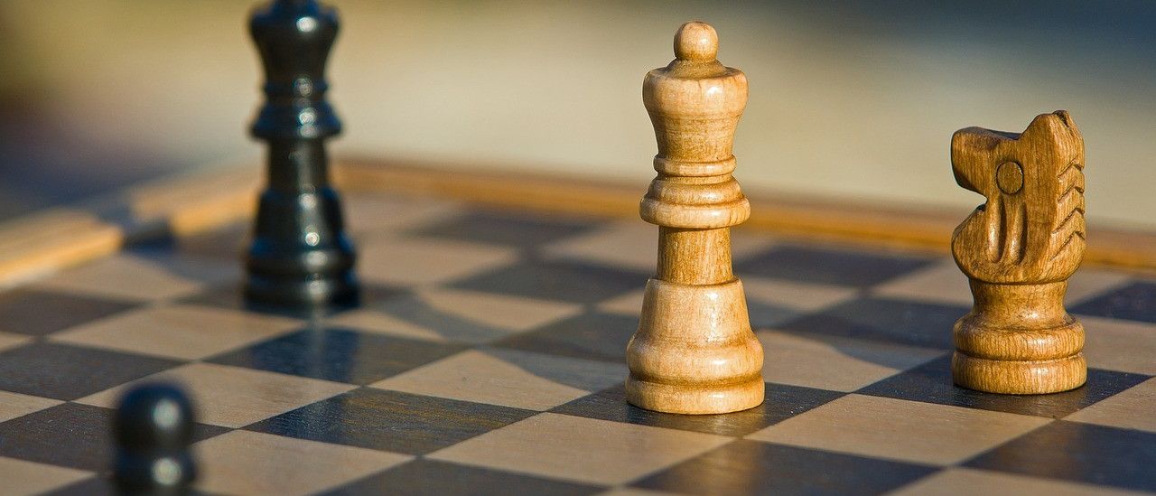 Ein Schachbrett mit einem hellbraunen König in der Mitte und einem schwarzen König auf der linken Seite.