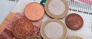 Ein Haufen verschiedener Euro-Münzen auf einem Dokument mit dem Titel 'Bewilligung von Leistungen zur Sicherung des Lebens'.