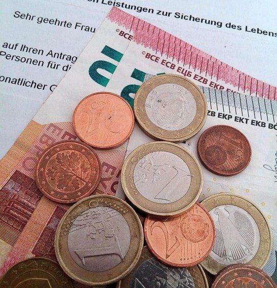 Ein Haufen verschiedener Euro-Münzen auf einem Dokument mit dem Titel 'Bewilligung von Leistungen zur Sicherung des Lebens'.