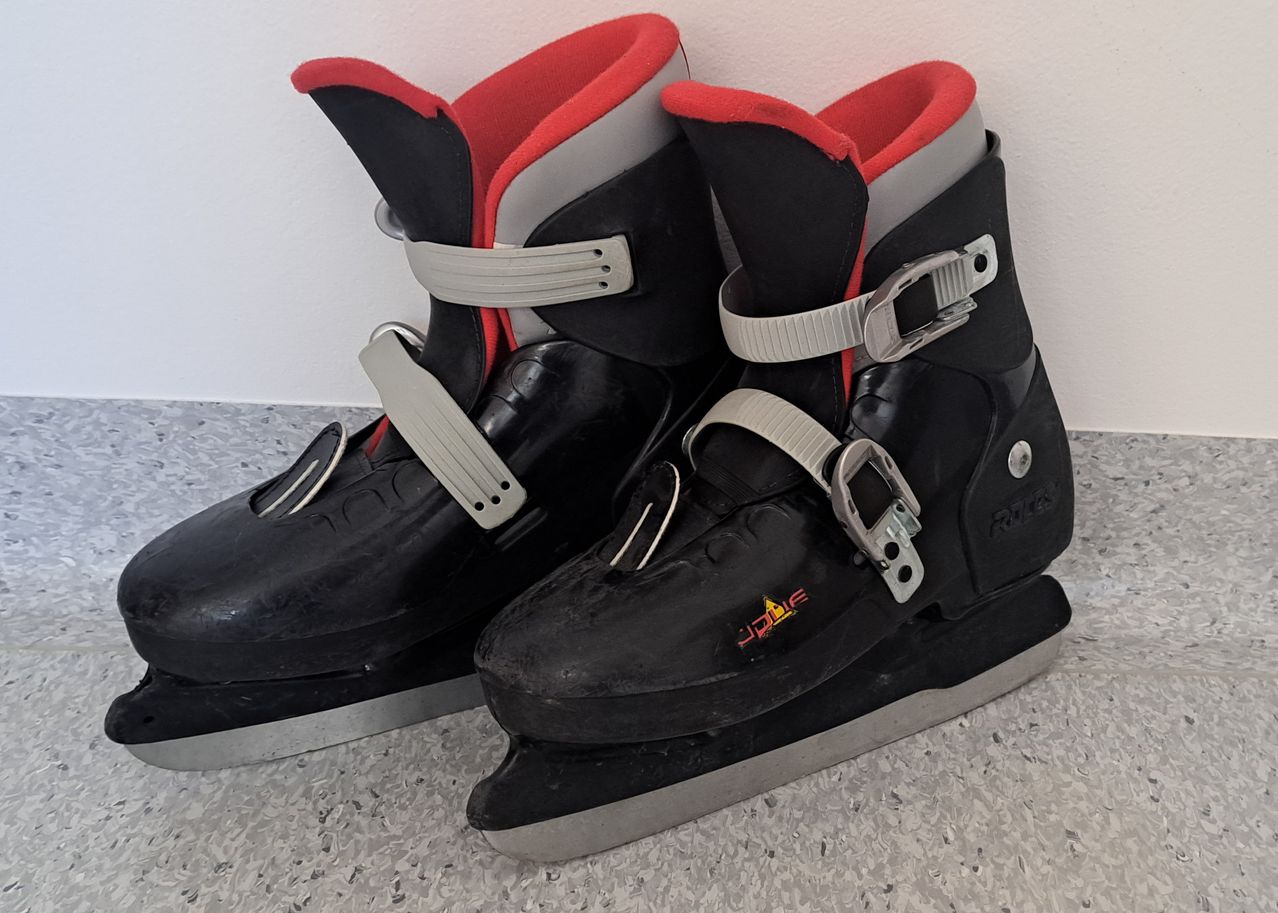 Ein Paar schwarzer und roter Eislaufschuhe mit Schnallen und Gurten. Sie haben eine silberne Metallklinge und ein rotes und schwarzes Design.