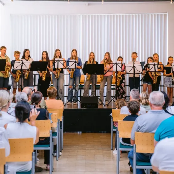 Eine Gruppe junger Musiker spielt mit Saxophonen auf der Bühne vor einem Publikum.