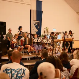 Eine Gruppe von Menschen spielt auf der Bühne mit Musikinstrumenten.