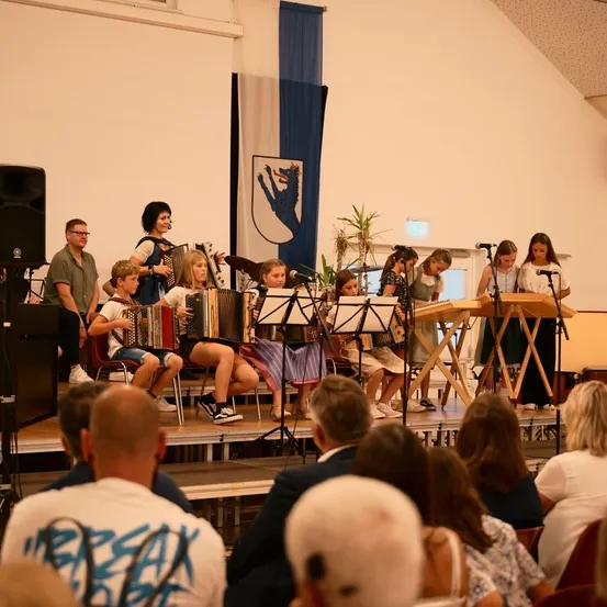 Eine Gruppe von Menschen spielt auf der Bühne mit Musikinstrumenten.