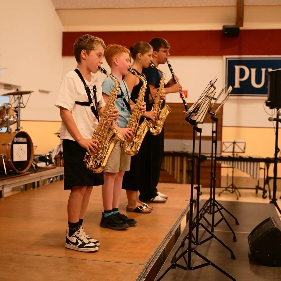 Eine Gruppe junger Musiker steht auf der Bühne und spielt Saxophon und andere Instrumente.