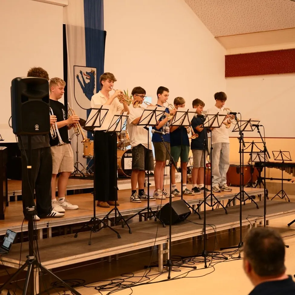 Eine Gruppe junger Musiker spielt auf der Bühne mit Trompeten und anderen Instrumenten.