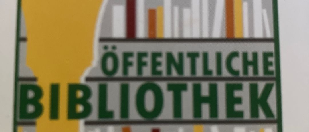 Ein Schild für eine öffentliche Bibliothek in Birkfeld, mit einem Bücherregal mit Büchern und einem gelben Bogen.