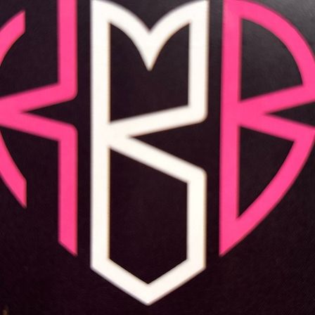 Eine schwarze Karte mit einem pinkfarbenen und weißen Herzmonogramm darauf. Das Monogramm besteht aus den Buchstaben 'KMB'.