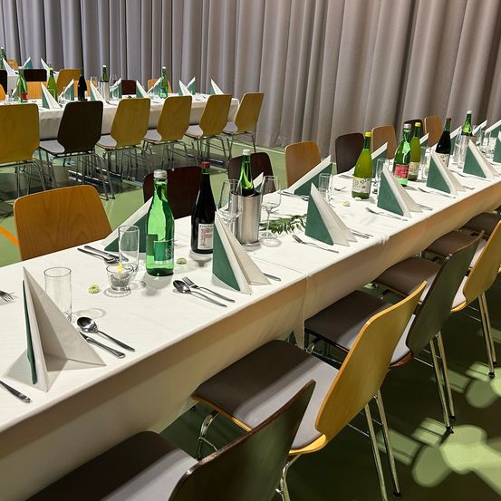 Bild enthält, People, Indoors, Chair, Furniture, Table, Tabletop, Hall, Crowd, Classroom, Audience