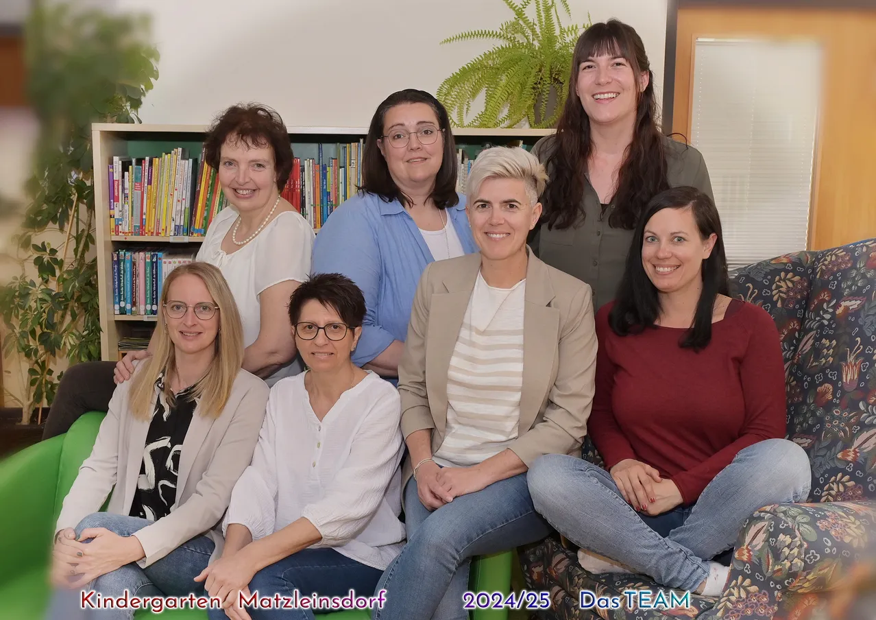Eine Gruppe lächelnder Frauen in verschiedenen Kleidungsstücken sitzt in einem Raum, möglicherweise einer Bibliothek, mit Büchern an den Regalen im Hintergrund. Das Bild hat einen Wasserzeichen des Jahres 2024/25.