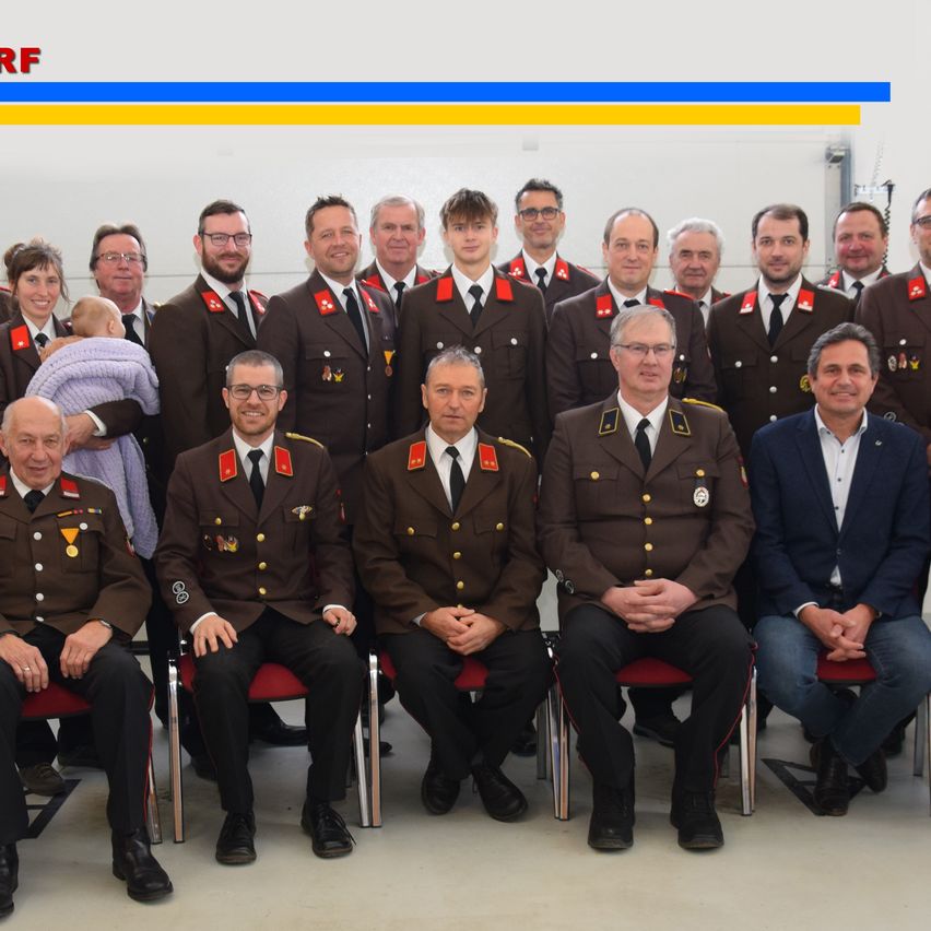 A group photo of people in uniform, including two men with medals, posing for a picture with a banner above.