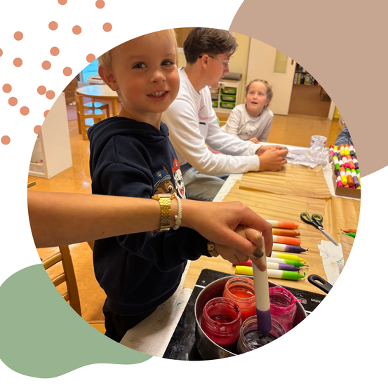 Kinder beschäftigen sich mit einer Malaktivität in verschiedenen Farben, wobei ein Junge einen Pinsel in Farbe taucht und ein anderer Junge in der Nähe sitzt.