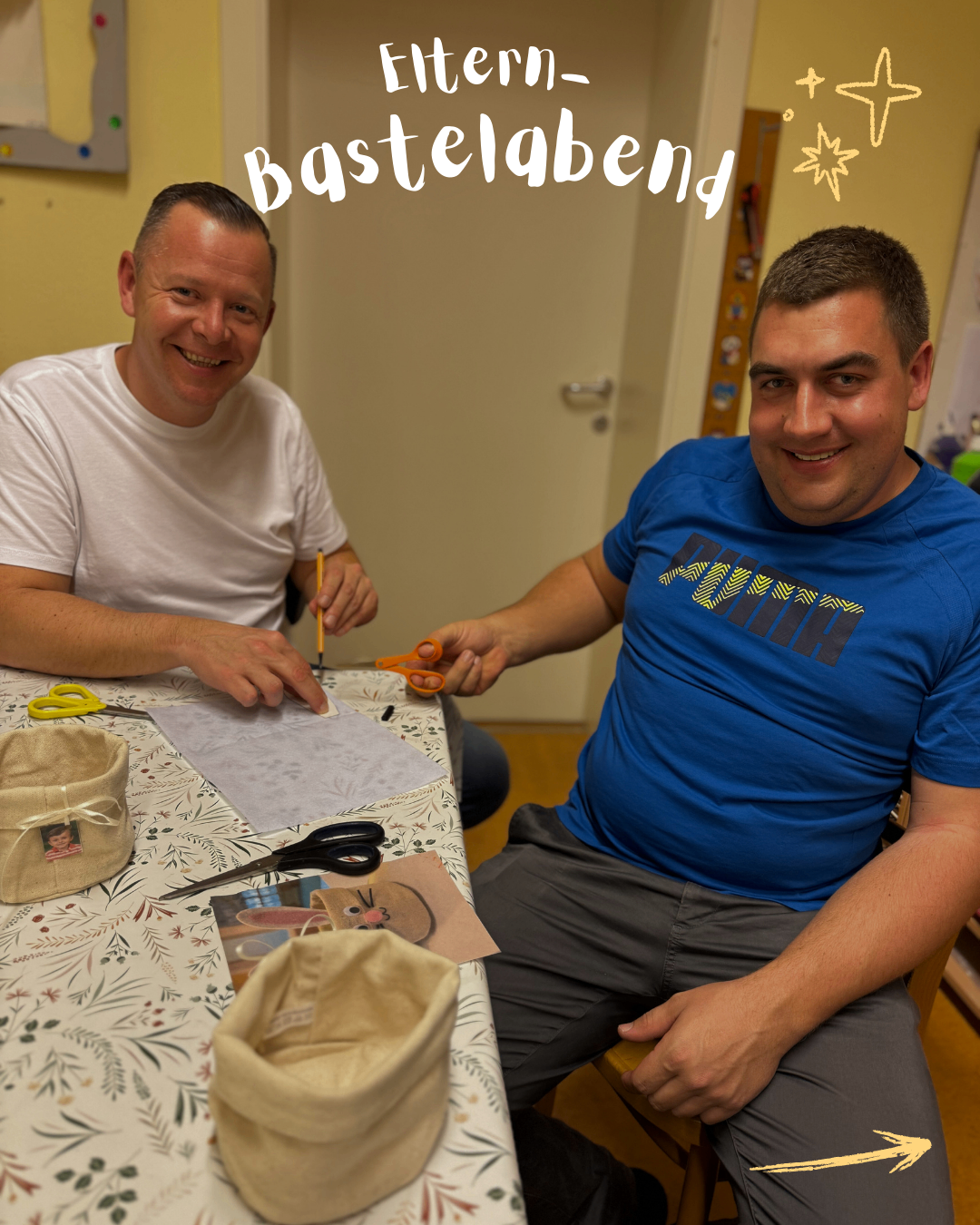 Zwei Männer sitzen an einem Tisch, lächeln und halten Scheren. Einer schneidet Papier, während der andere zusieht. Ein Korb und eine Karte mit einem Kinderbild liegen auf dem Tisch. Das Wort Bastelabend steht darüber.