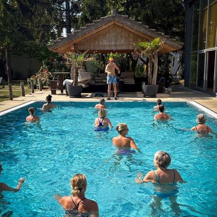 Eine Gruppe von Frauen schwimmt im Pool, während ein Mann an der Seite steht.
