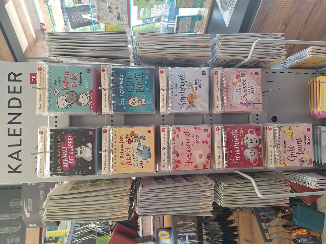 A store shelf filled with various colorful calendars, each with unique designs and titles, arranged in rows.