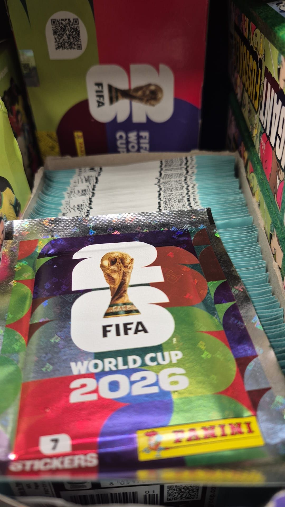 Ein Nahaufnahme eines bunten Pakets mit dem FIFA-Weltmeisterschaftslogo 2026 und einer goldenen Trophäe in der Mitte.