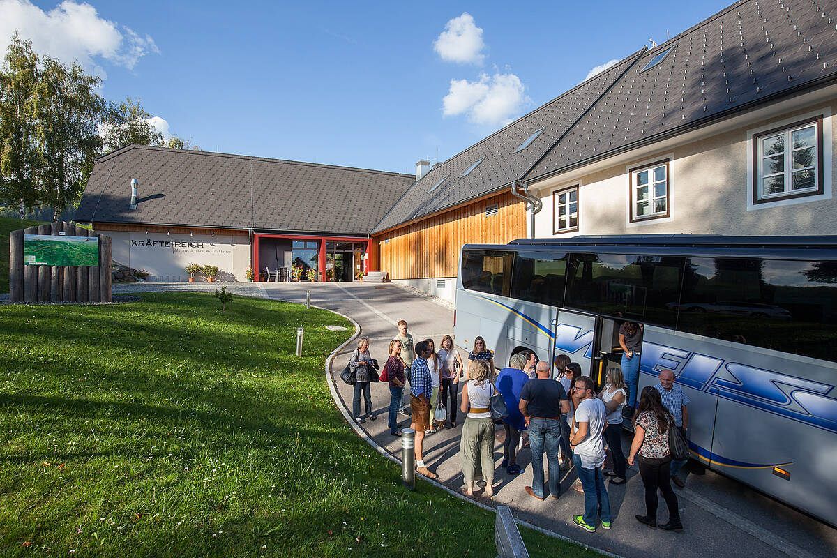 Touristen stehen vor einem modernen Gebäude. Sie stehen vor einem Bus mit offener Tür.