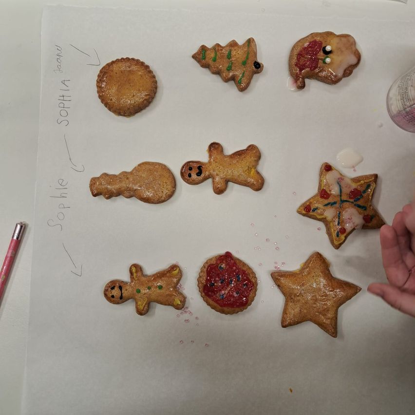 Eine Sammlung von Lebkuchenplätzchen ist auf einer weißen Oberfläche angeordnet, einschließlich Lebkuchenmänner, eines Sterns und eines Weihnachtsbaums.