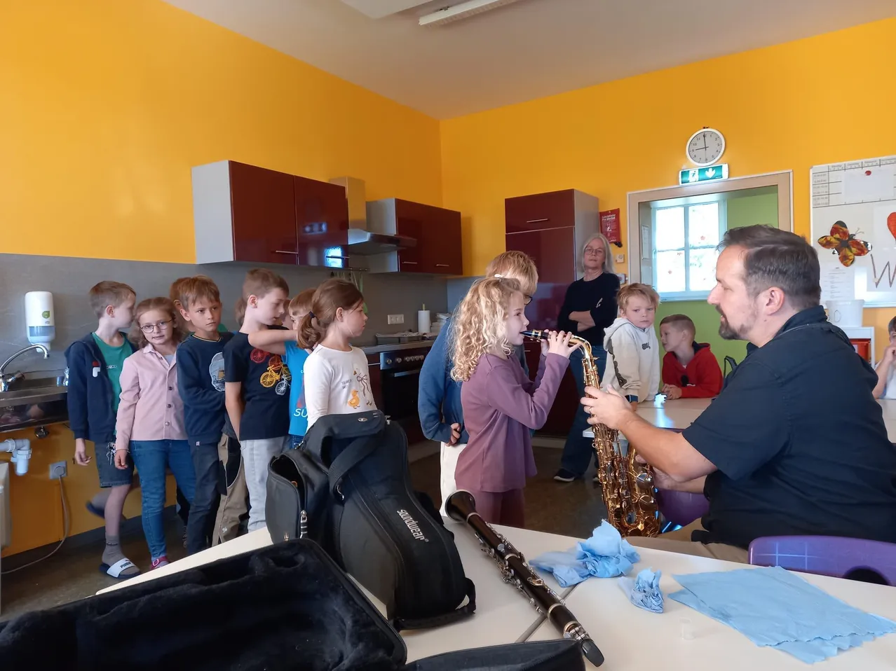 Ein Mann spielt Saxophon, während eine Gruppe von Kindern zuschaut.