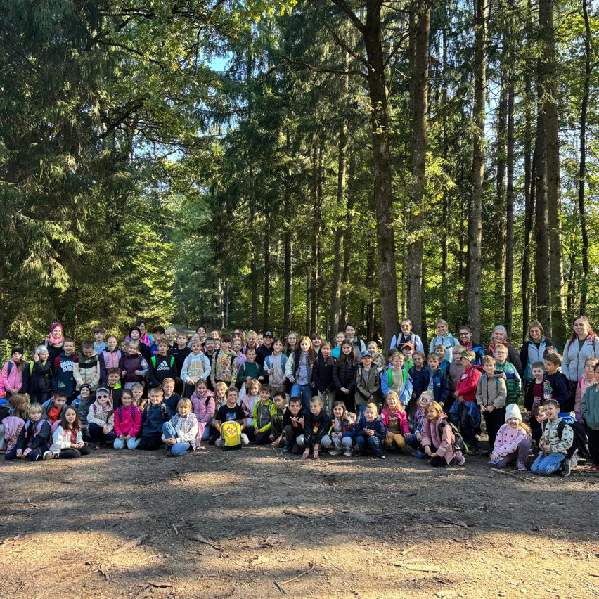 Eine Gruppe von Kindern und Erwachsenen posiert für ein Foto im Wald.