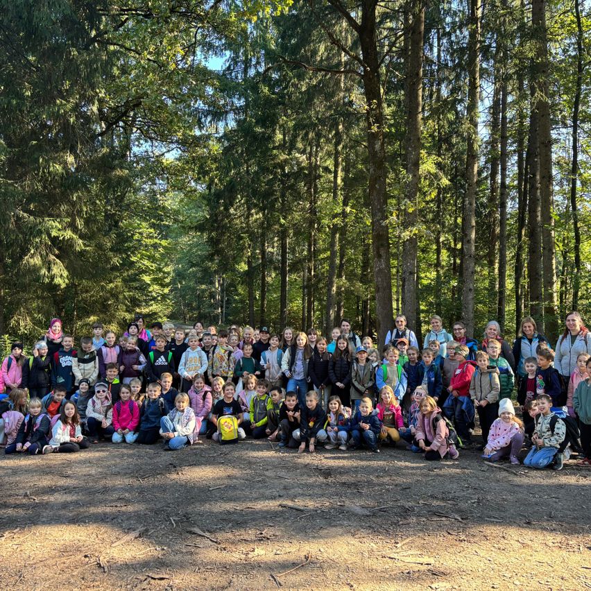 Eine Gruppe von Kindern und Erwachsenen posiert für ein Foto im Wald.
