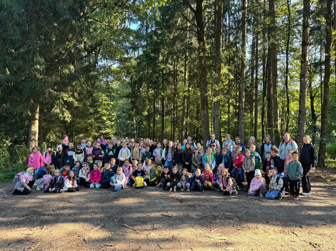 Eine Gruppe von Kindern und Erwachsenen posiert für ein Foto im Wald.