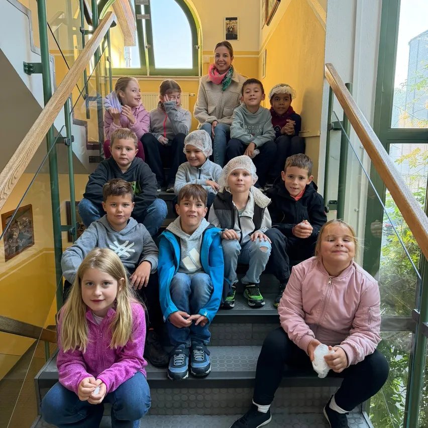 Eine Gruppe von Kindern und einer erwachsenen Frau posiert für ein Foto auf einer Treppe.