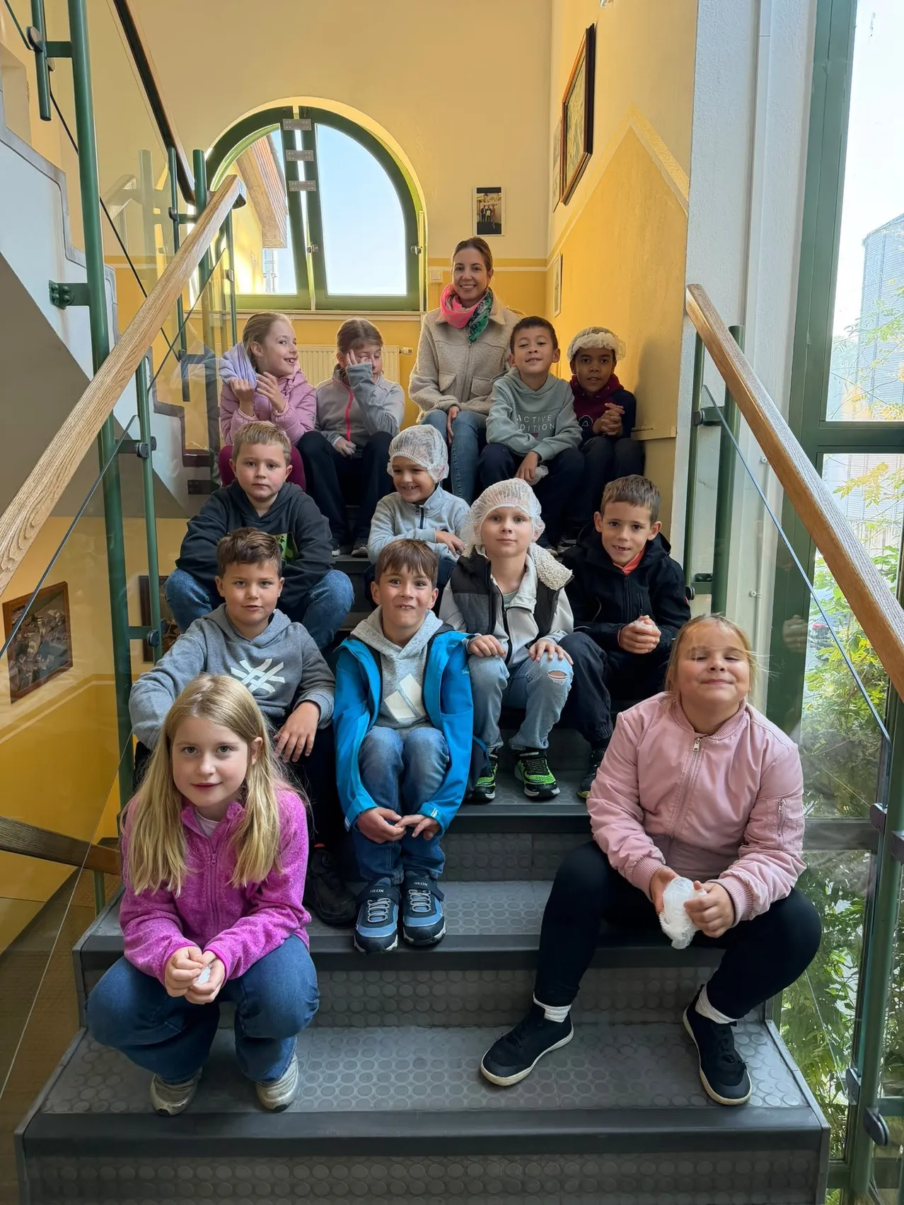 Eine Gruppe von Kindern und einer erwachsenen Frau posiert für ein Foto auf einer Treppe.