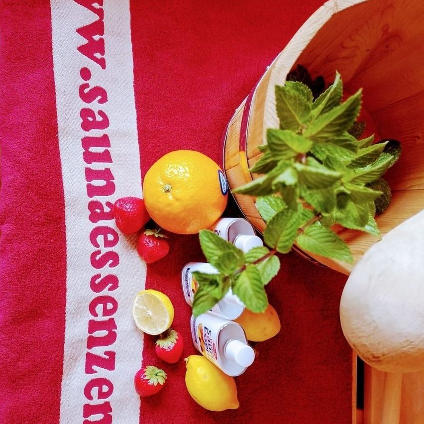 Ein Holzschale mit Minzblättern, einer Zitrone und Erdbeeren auf einem roten Tuch mit dem Wort 'Wassersensoren'. Es gibt auch Flaschen mit weißen Kappen.