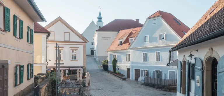 Eine Kopfsteinpflasterstraße in einer malerischen europäischen Stadt mit traditionellen Gebäuden und blauem Himmel.