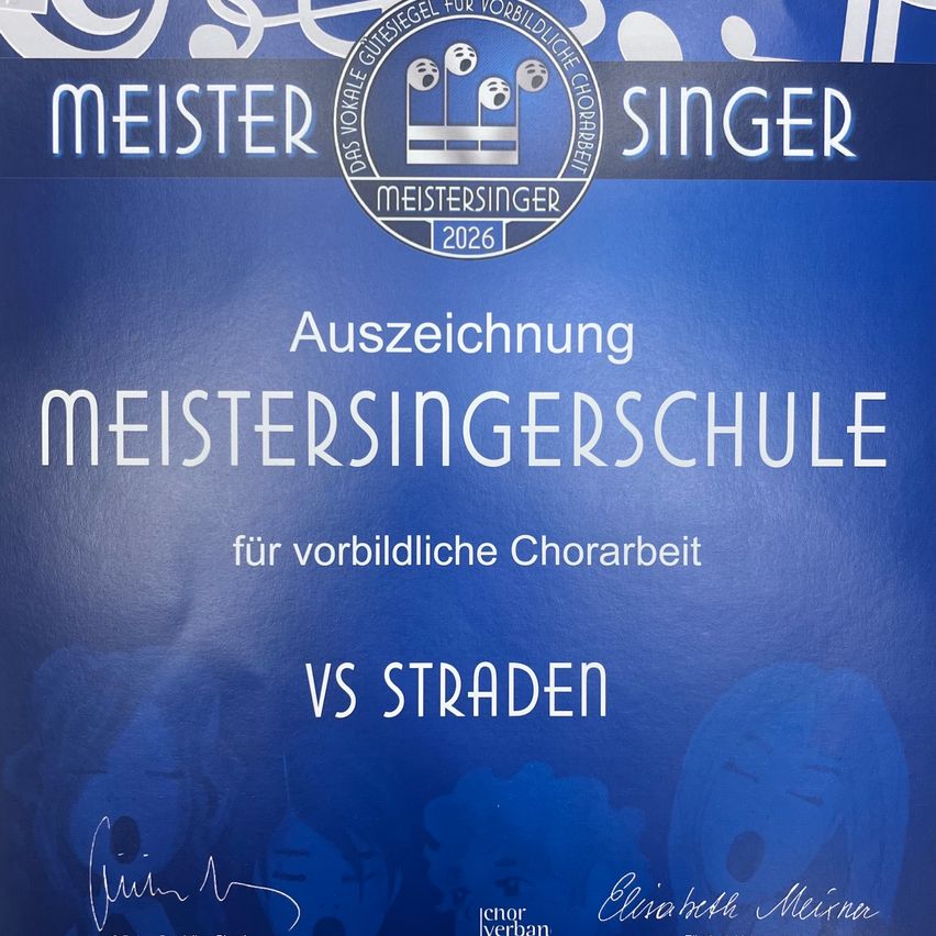 Ein blaues Zertifikat mit Text und Logo. Es steht 'Meistersingerschule' für vorbildliche Chorarbeit. Der Name 'VS Straden' steht darunter. Eine Unterschrift und ein Stempel sind links.