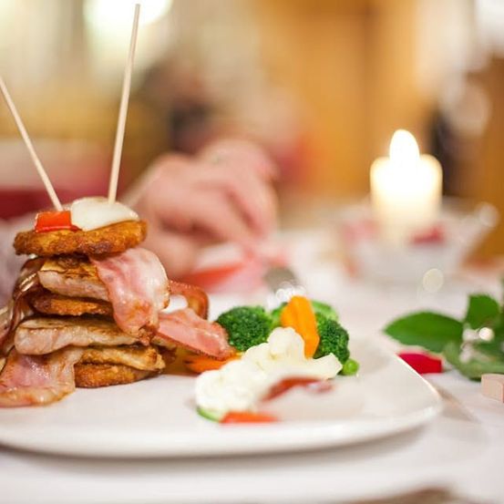 Ein Teller mit Speck-Ei-Sandwich und Gemüse auf einem Tisch mit einer Kerze und Blumen.