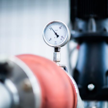 Nahaufnahme eines Druckmessgeräts mit einem roten Schlauch, das einen Druck von 10 bar anzeigt.