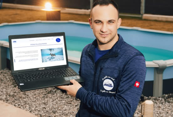 Ein Mann hält einen Laptop vor einem oberirdischen Pool, lächelt, mit einer Schwimm-Website auf dem Laptop-Bildschirm.