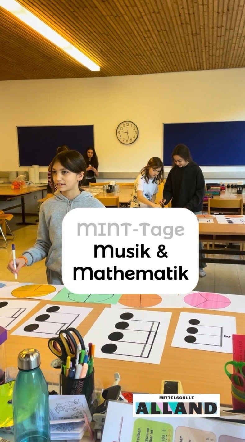 A classroom with students engaged in activities; one student holds a pencil, and another works on a table with diagrams. A clock on the wall reads 10:10.