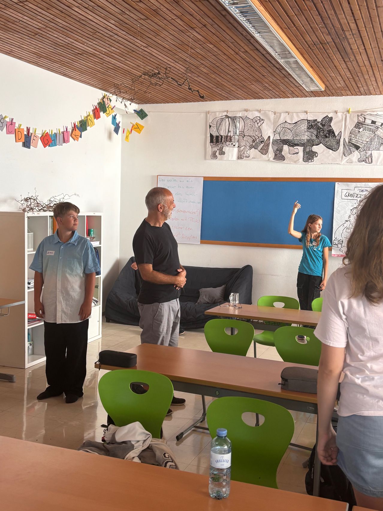 Schüler und Lehrer in einem Klassenzimmer mit Kunstwerken an der Wand