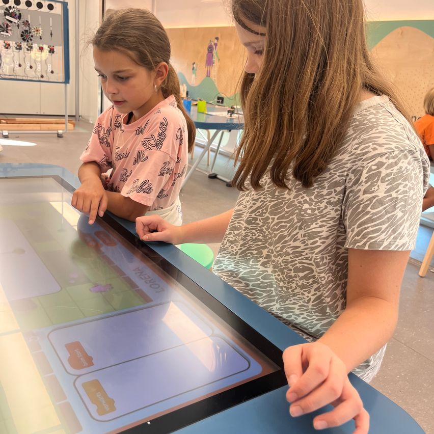 Zwei Mädchen spielen an einem interaktiven Tisch in einem Museum in Wien