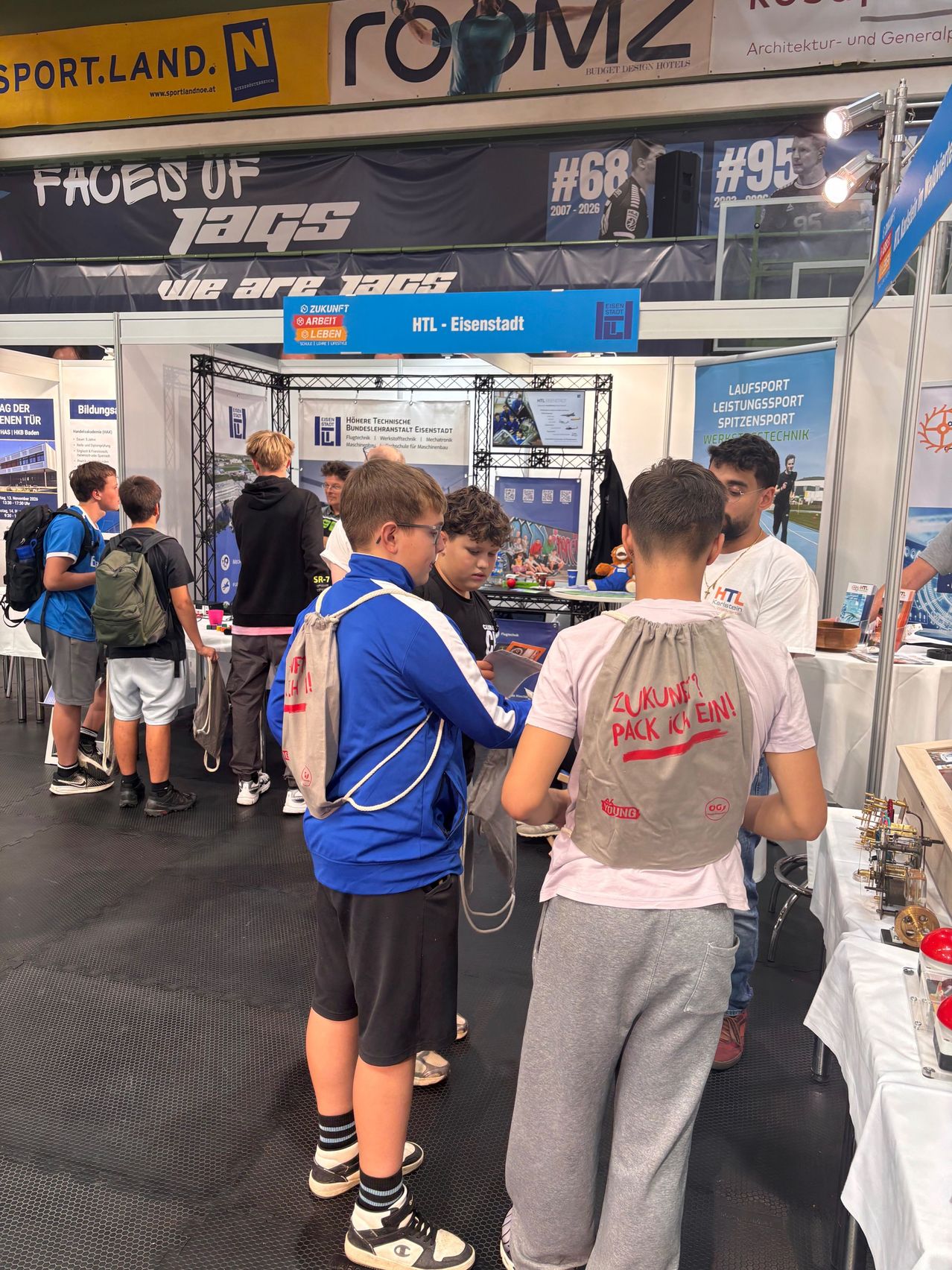Jugendliche mit Rucksäcken vor dem Stand der HTL Eisenstadt auf einer Messe