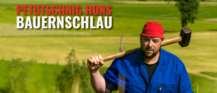 Ein Mann in einem blauen Hemd und rotem Hut, der einen Baseballschläger hält, steht in einem Grasfeld mit den Worten Schnig Hons Rnschlau über ihm.