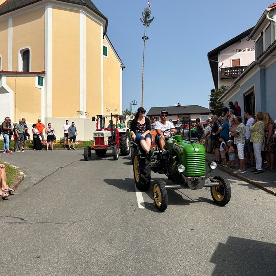Bild enthält, Neighborhood, City, Street, Antique Car, Model T, Vehicle, Person, Wheel, Building, Motorcycle